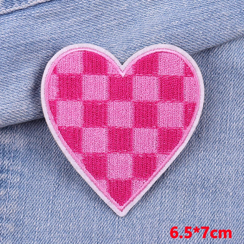 Heart-shaped pink and white checkered patch on denim fabric with size label.