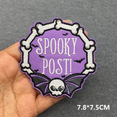 Embroidered patch with 'Spooky Post!' text held by a hand on a gray background