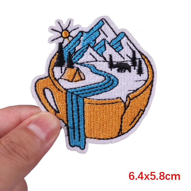 Patch of a mug with mountains and a flower held by a hand, size 6.4x5.8cm.