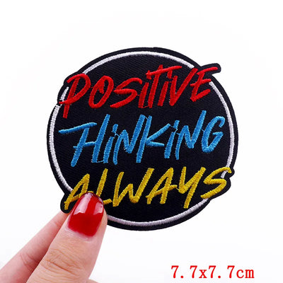 Embroidered patch with 'Positive Thinking Always' text held by a hand on a white background