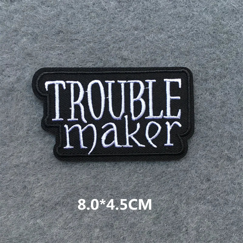 Embroidered patch with 'TROUBLE maker' text on a gray background