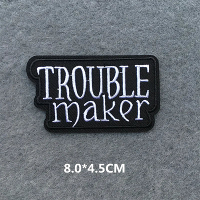 Embroidered patch with 'TROUBLE maker' text on a gray background
