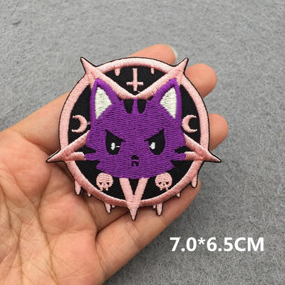 Purple cat-like creature patch held in a hand with a gray background