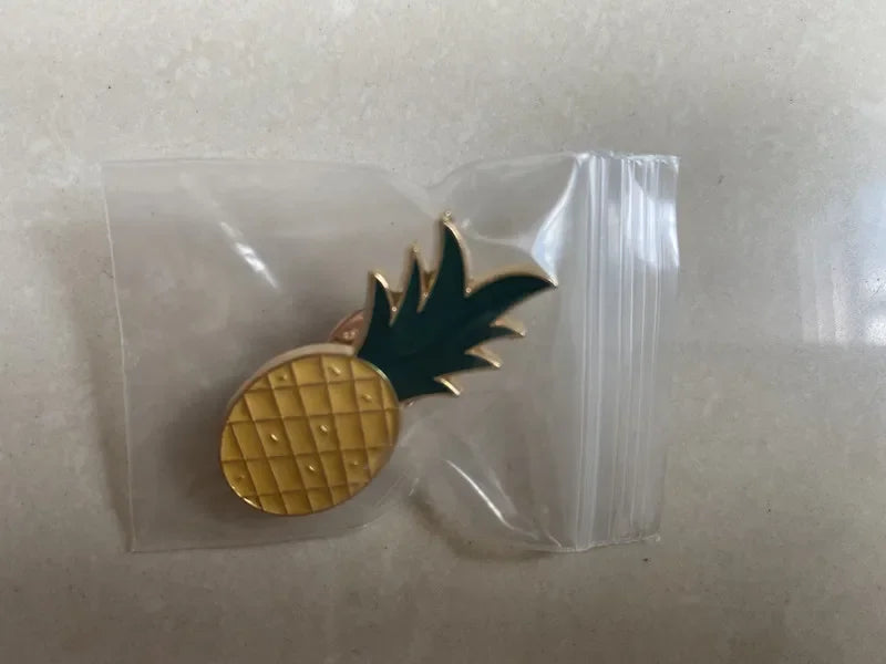 Pineapple-shaped gold pin on a white background