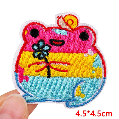 Colorful embroidered patch of a cartoon character with a flower, held by a hand on a white background.