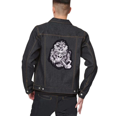 Black denim jacket with a graphic design on the back, worn by a person.