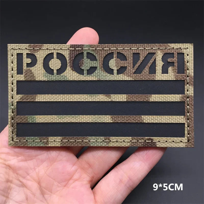 Russia flag Camouflage patch held in a hand against a dark background