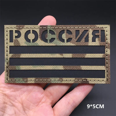 Russia flag Camouflage patch held in a hand against a dark background