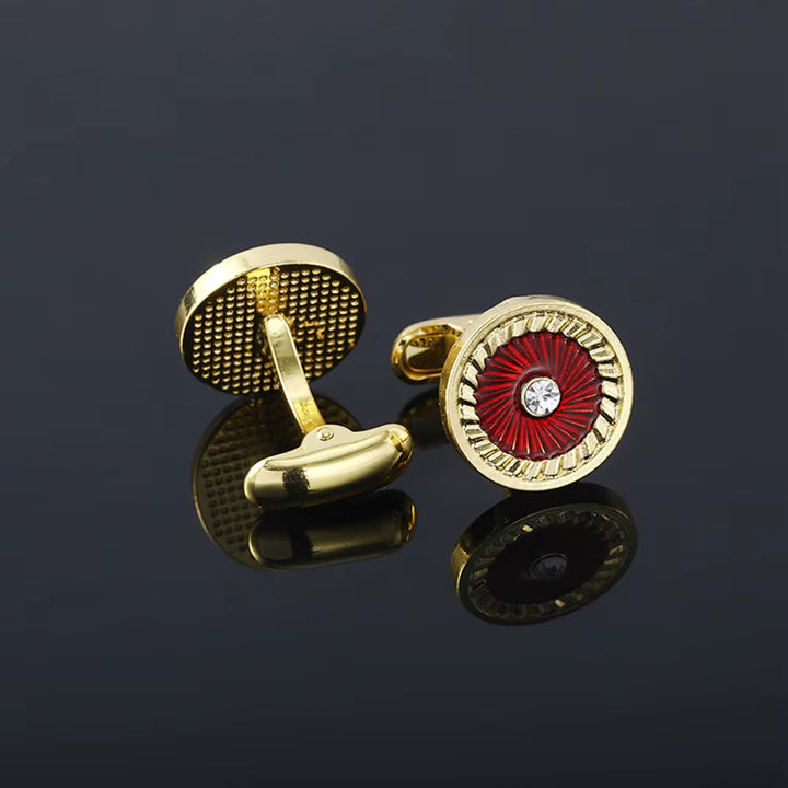Gold and red cufflinks with a central gemstone on a dark background