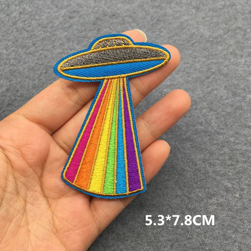 Colorful UFO patch held in a hand with a gray background