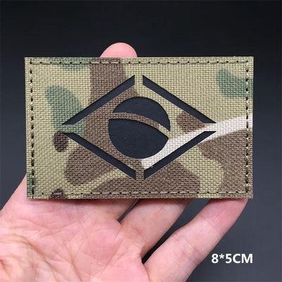 Brazil flag Camouflage patch with a black symbol held in a hand against a dark background