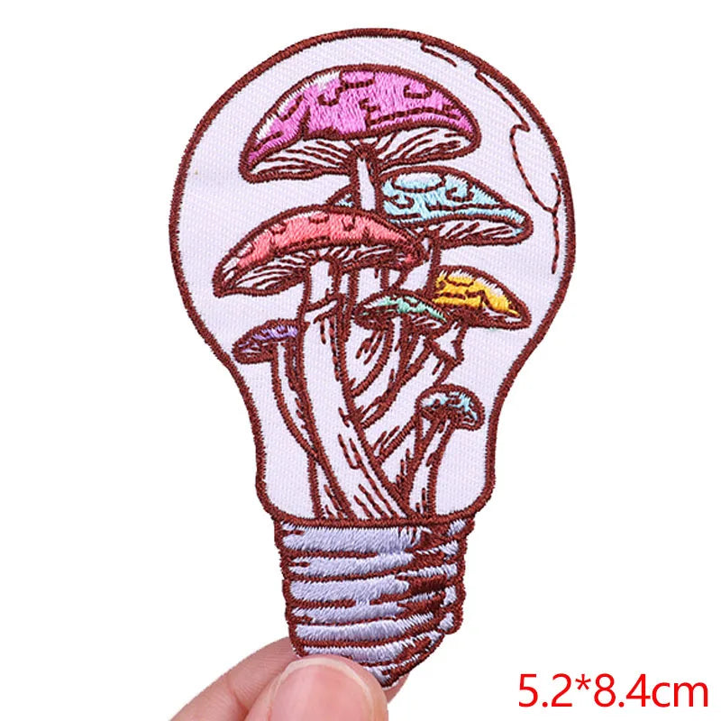 Embroidered patch of mushrooms inside a light bulb on a white background