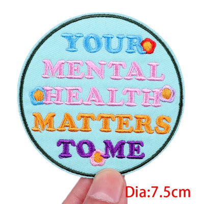 Circular patch with embroidered text 'Your Mental Health Matters to Me' held by a hand.