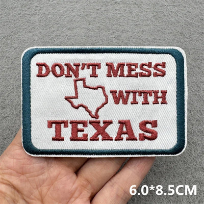 Embroidered patch with 'Don't Mess with Texas' text held in a hand against a gray background