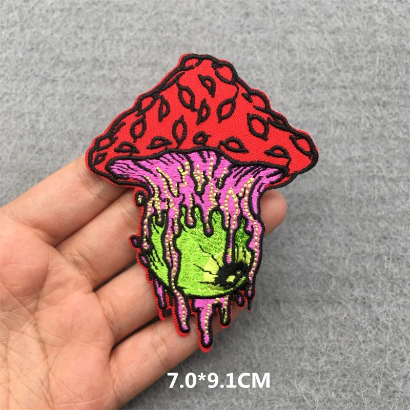 Colorful mushroom-shaped patch held by a hand on a gray background