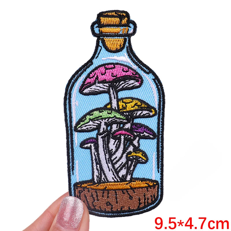 Embroidered patch of mushrooms in a bottle held by a hand with measurement text.