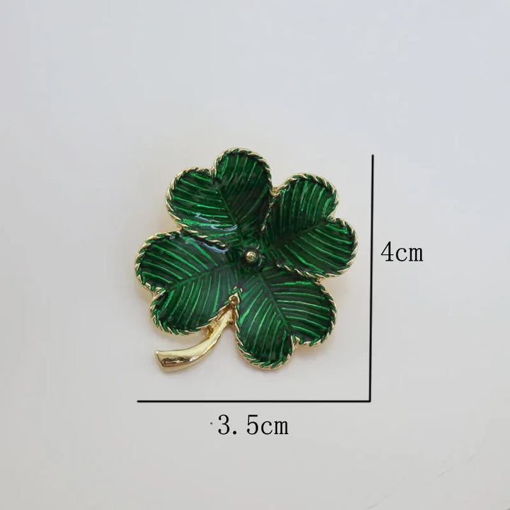 Green four-leaf clover brooch with gold accents on a white background, showing measurements.