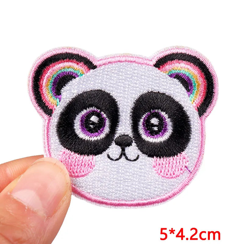 Embroidered patch of a panda face with rainbow ears held by a hand, on a white background.