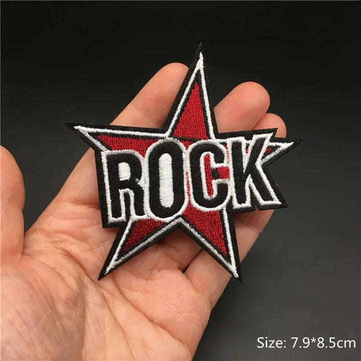 Hand holding a red black and white ROCK star embroidered iron-on patch 7.9x8.5cm on a dark background