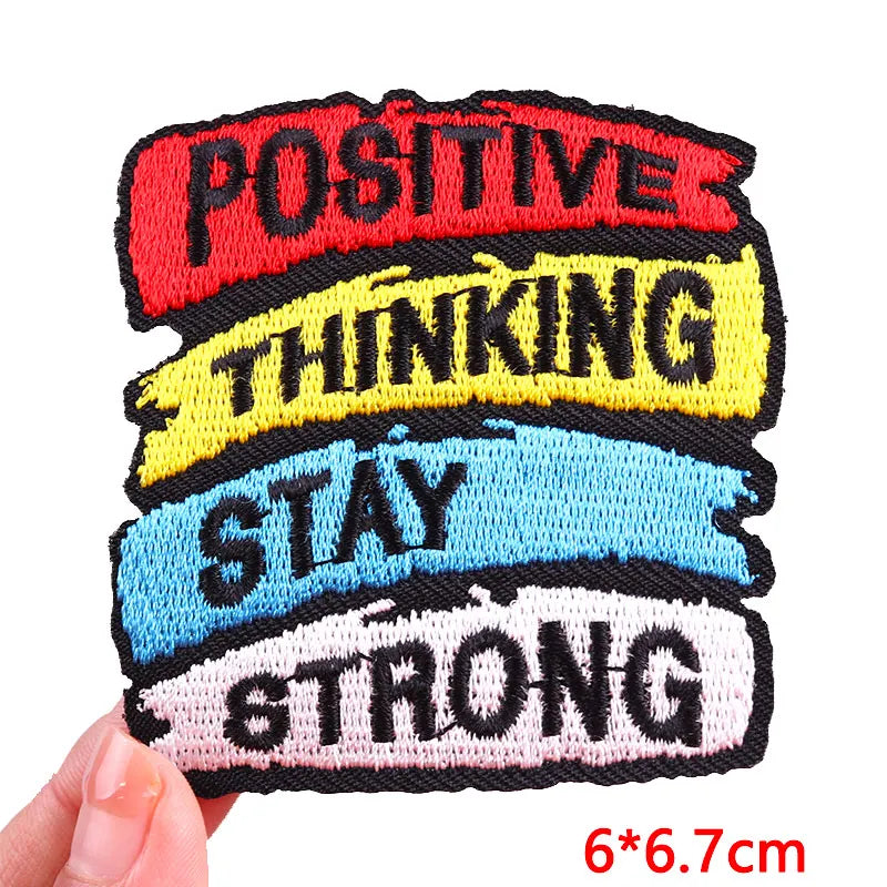 Motivational patch with text 'Positive Thinking Stay Strong' held by a hand on a white background.