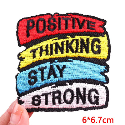 Motivational patch with text 'Positive Thinking Stay Strong' held by a hand on a white background.