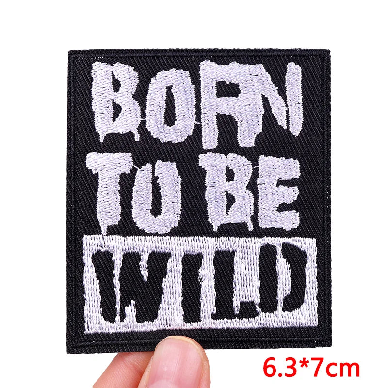 Embroidered patch with 'BORN TU BE WILD' text held by a hand, with dimensions displayed.