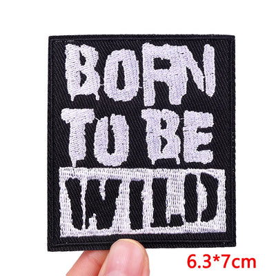 Embroidered patch with 'BORN TU BE WILD' text held by a hand, with dimensions displayed.