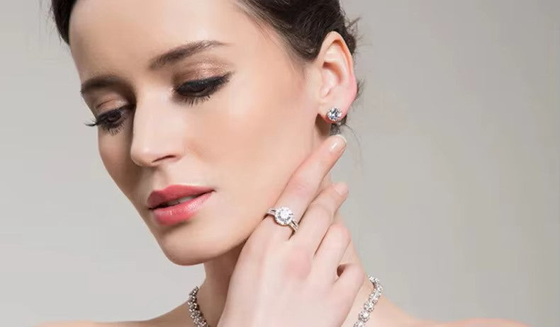Woman wearing crystal earrings and ring on a neutral background