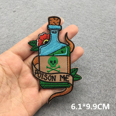 Embroidered patch of a bottle labeled 'Poison Me' held by a hand on a gray background.