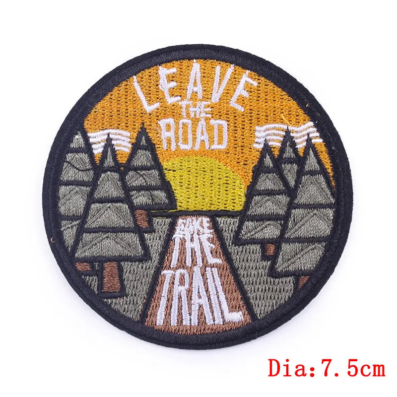 Round embroidered patch with mountains and text 'Leave the Road, Take the Trail' on a white background.
