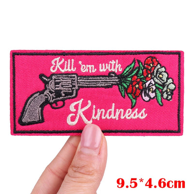 Pink patch with gun and flowers design held by a hand, on a white background.