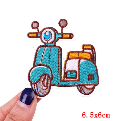 Embroidered scooter patch held by a hand with a white background