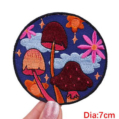 Circular embroidered patch with mushrooms and flowers held by a hand, labeled 'Diameter: 7cm'.