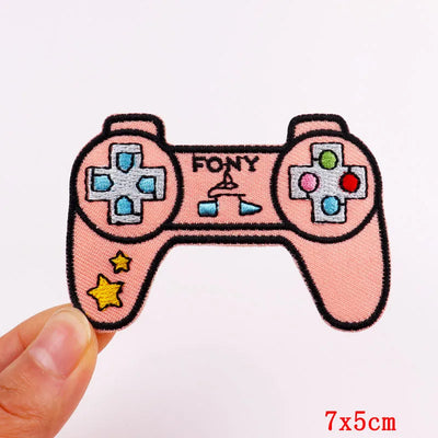Pink game controller patch held by a hand on a white background