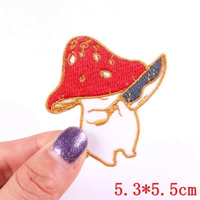 Red mushroom-shaped patch held by a hand with purple nail polish on a white background.