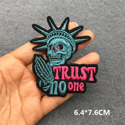Skull-like patch with 'Trust No One' text held in a hand on a gray background