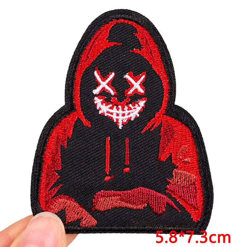 Embroidered patch with a red and black design held by a hand on a white background.