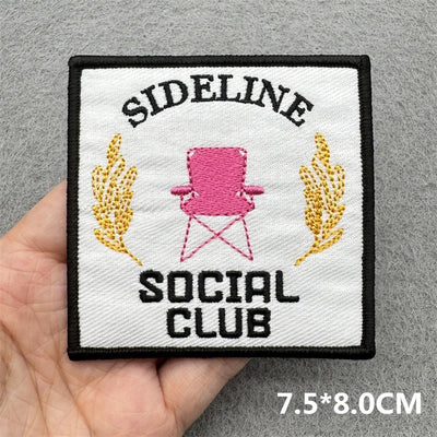 Patch with 'Sideline Social Club' design held by a hand on a gray background
