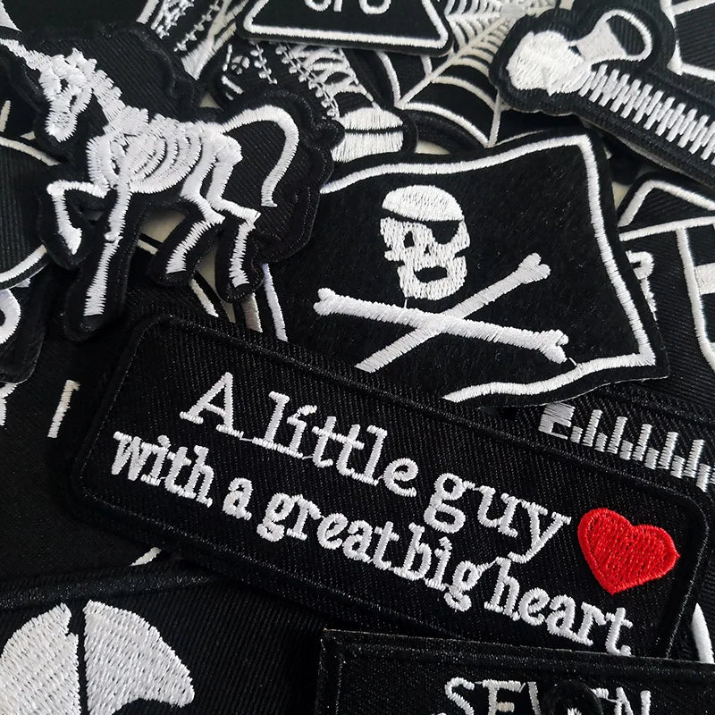 Collection of black and white patches with text and designs, including a pirate flag and motivational quote.