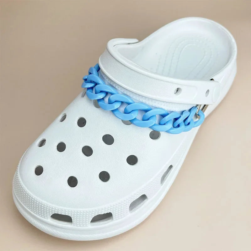 White clog shoe with a blue chain accessory on a beige background