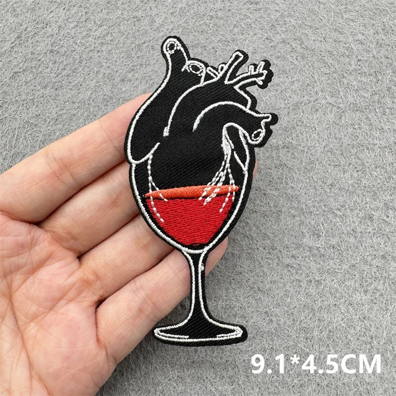 Heart-shaped wine glass patch held by a hand on a gray background