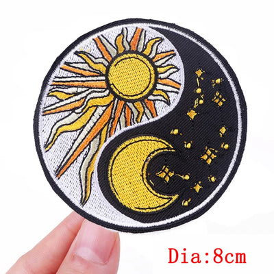 Circular patch with sun and moon design held by a hand, on a white background.
