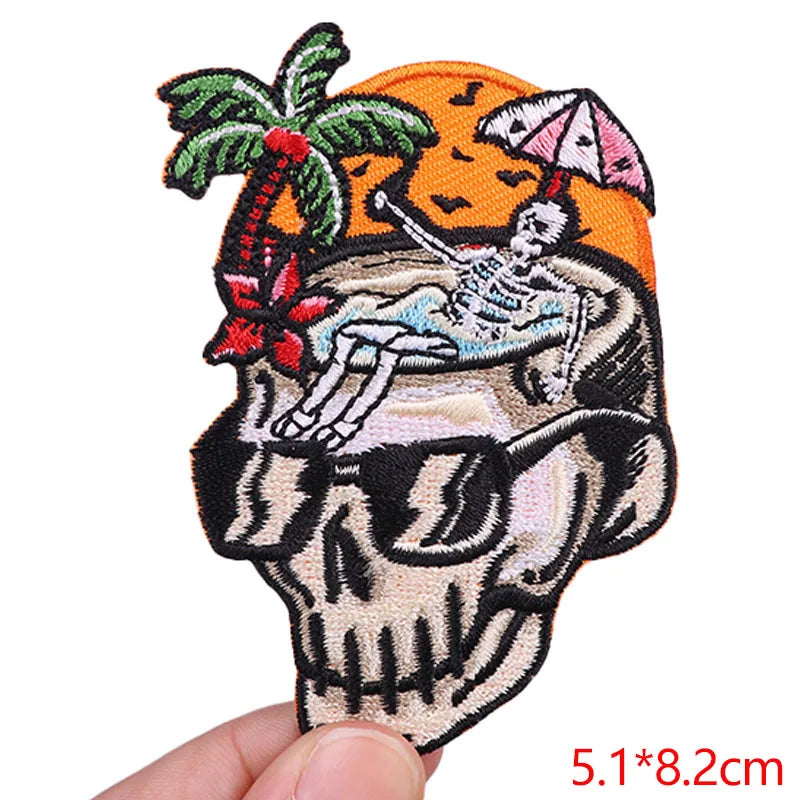 Embroidered patch with skeleton on a beach scene held by a hand.