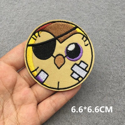 Circular patch with a cartoon character held by a hand on a gray background