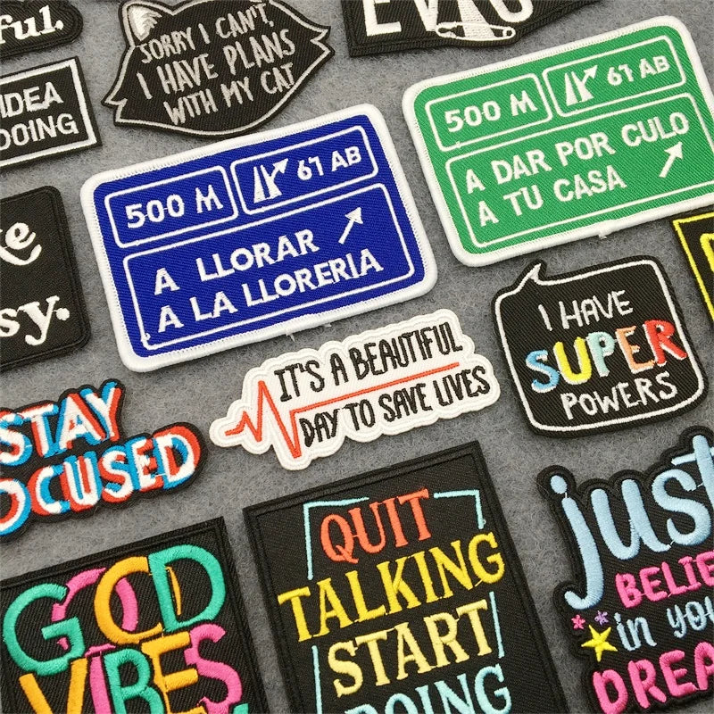 Collection of colorful patches with motivational and humorous text on a gray background