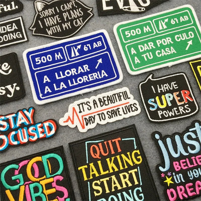 Collection of colorful patches with motivational and humorous text on a gray background