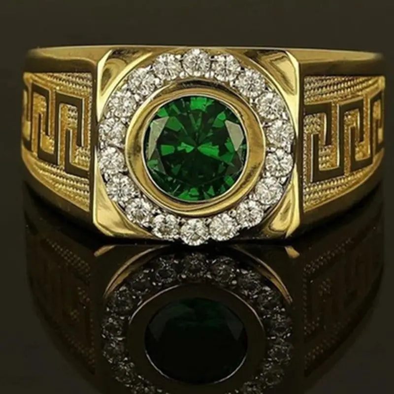 Gold tone ring featuring a large, round green gemstone surrounded by small zircon. The band has intricate designs, reflecting a luxurious and elegant tone.
