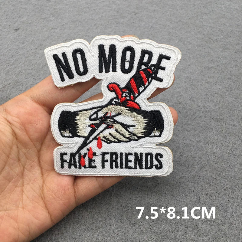 Embroidered patch with 'No More Fake Friends' text held in a hand on a gray background