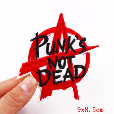 Embroidered patch with 'Punk's Not Dead' text held by a hand on a white background