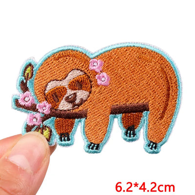 Embroidered patch of a sloth with flowers held between fingers, size 6.2*4.2cm.